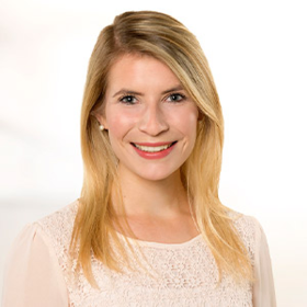 Lächelndes Porträt einer Frau mit langen blonden Haaren und weißer Spitzenbluse.
