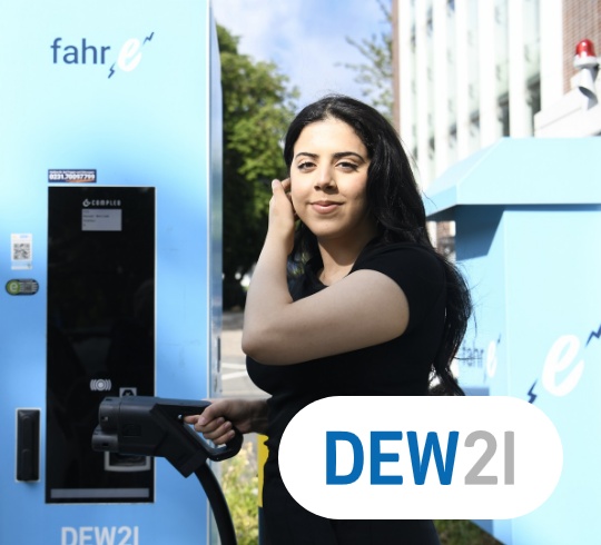 Eine Frau lädt ein Elektrofahrzeug an einer DEW21-Ladestation auf. Im Vordergrund ist das DEW21-Logo zu sehen.